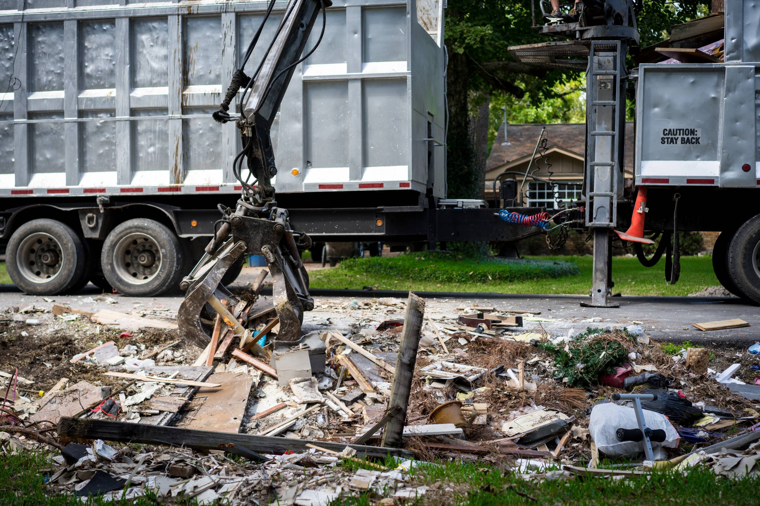 Large truck picking up trash and debris outside of neighborhoods devastated by Hurricane Harvey
